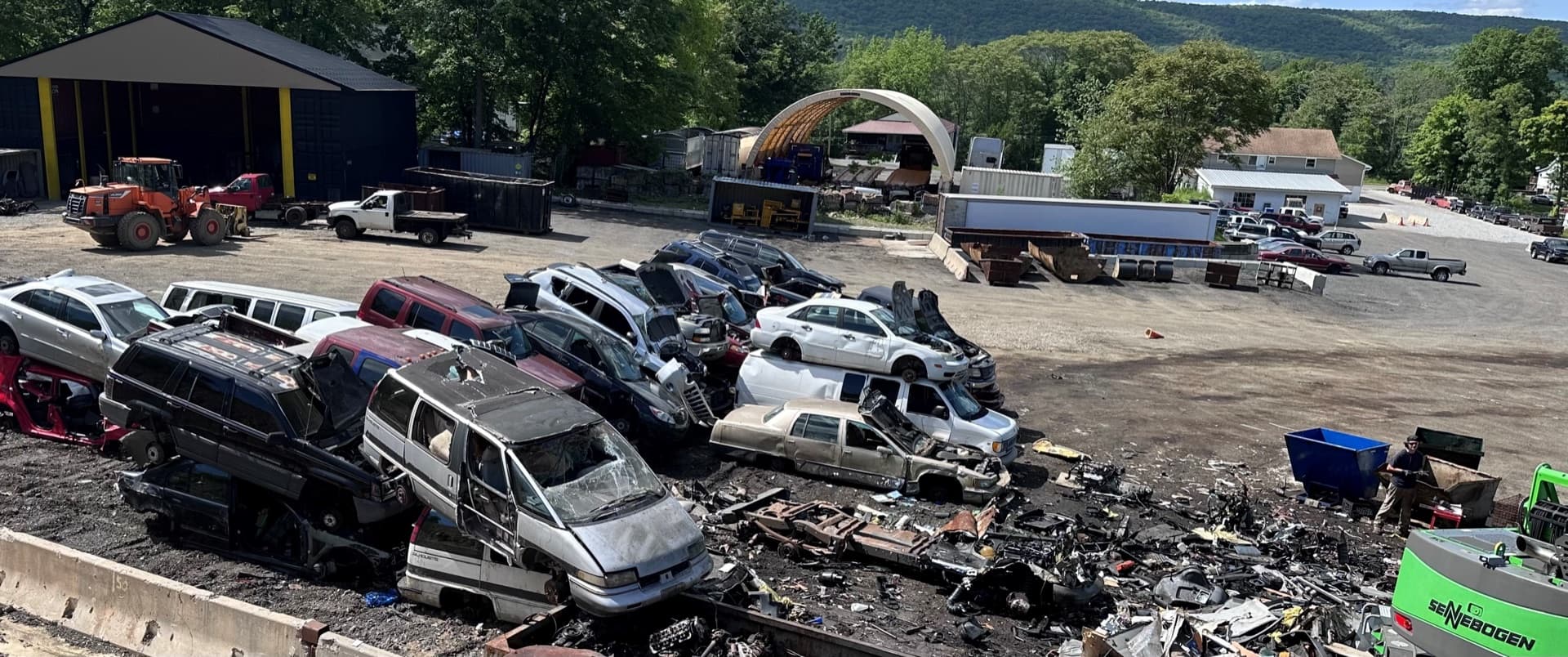 The AMR yard — rows of vehicles, working machinery, and the Sussex County hills behind